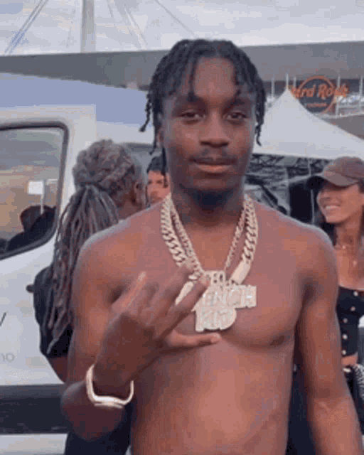 a shirtless man wearing a necklace and a bracelet is giving the middle finger .