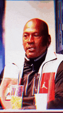 a man wearing a red and white air jordan jacket looks at the camera
