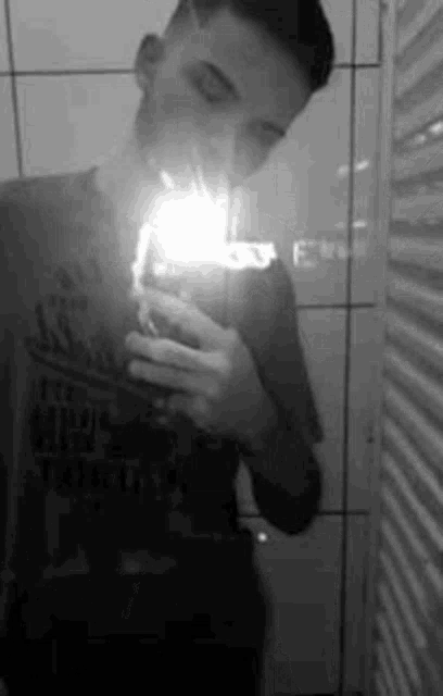 a man is taking a selfie in a bathroom with his phone .
