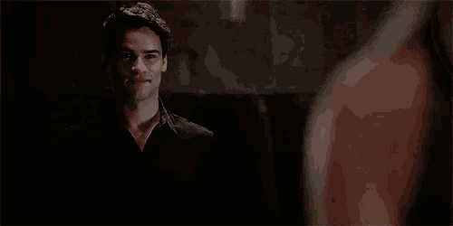 a man in a black shirt is waving his hand in front of a woman .