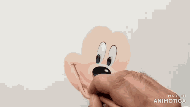 a person is drawing a mickey mouse face with a pencil on a piece of paper .