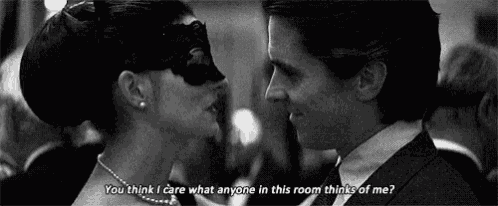 a man and a woman are looking at each other in a black and white photo . the man is wearing a mask .