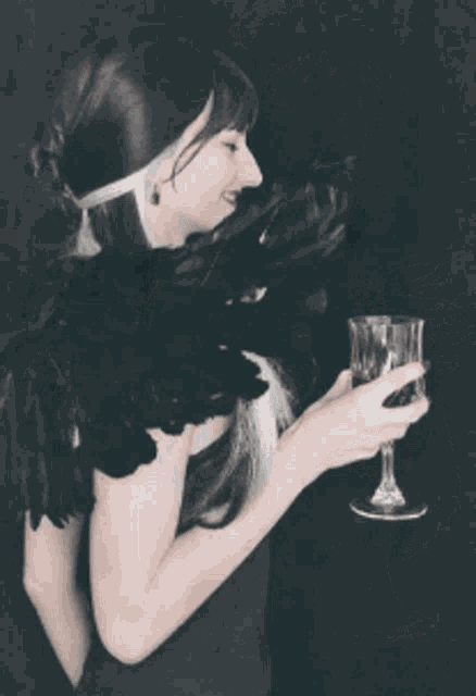 a woman in a black dress is holding a wine glass