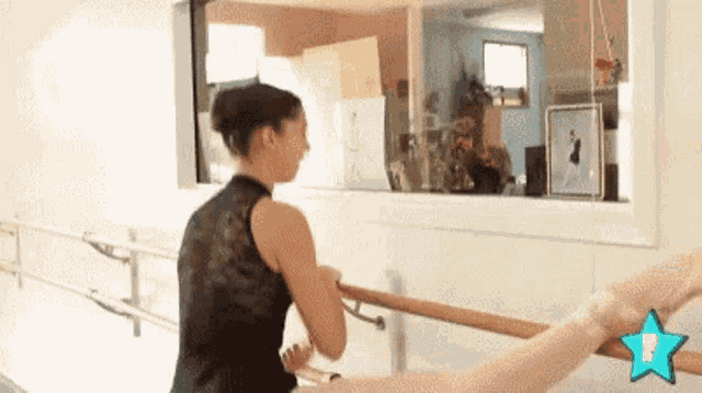 a woman is standing in front of a mirror in a dance studio