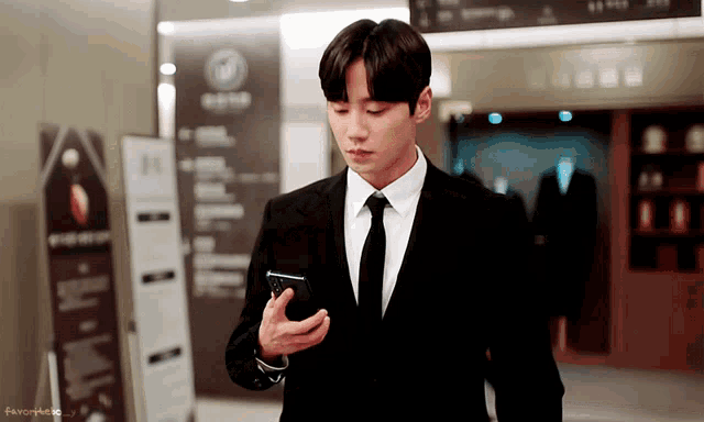 a man in a suit and tie looking at his phone