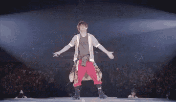 a man with red hair is standing on a stage with his eyes closed and his arms outstretched .