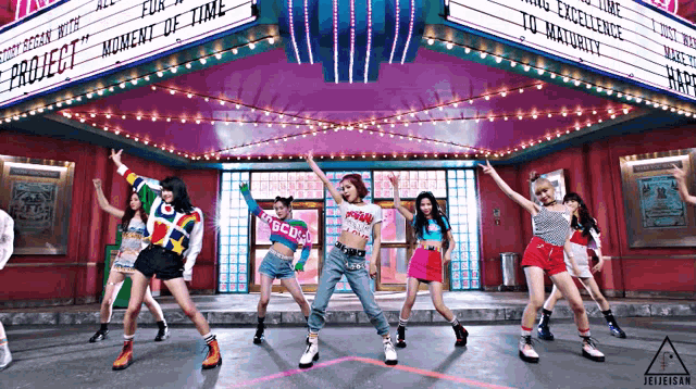 a group of girls are dancing in front of a project sign