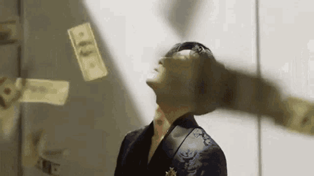 a man in a suit is standing in front of a bunch of money falling from the sky .