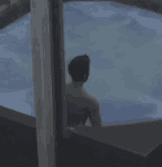 a man is sitting in a hot tub looking out of a window .