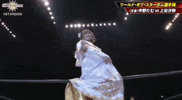 a woman in a white and gold dress is standing in a wrestling ring
