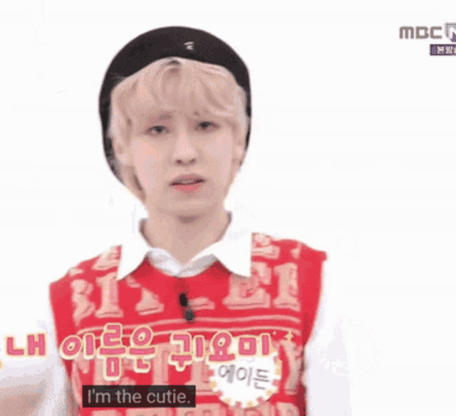 a young man wearing a red vest that says i 'm the cutie on it
