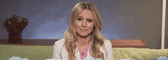 a woman in a white jacket and pink shirt is sitting on a green couch and smiling .