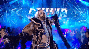 a woman in a fur coat is walking on a stage in front of a crowd .