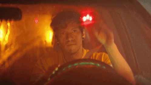 a man in a yellow shirt is sitting in a dark room with red lights