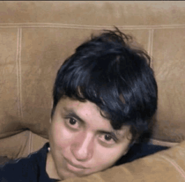 a close up of a person laying on a couch with their head on a pillow