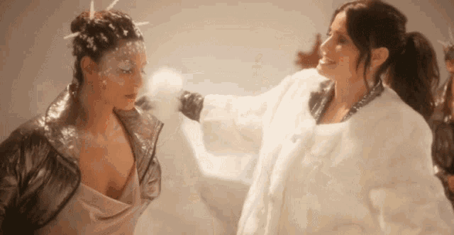 a woman in a white fur coat is standing next to another woman