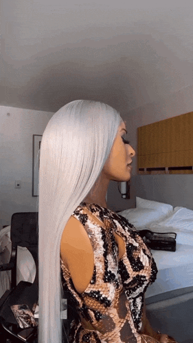 a woman with long white hair and a snake print top