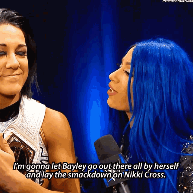 a woman with blue hair talks into a microphone and says i 'm gonna let bayley go out there all by herself
