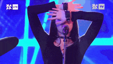 a woman singing into a microphone in front of a tv screen that says lite on it