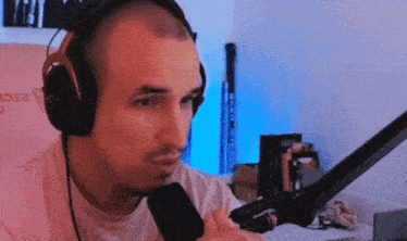 a man wearing headphones is sitting in front of a microphone with a pink chair behind him that says a2cl