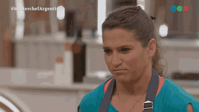 a woman in a blue shirt and apron is on a tv show called master chef argentina