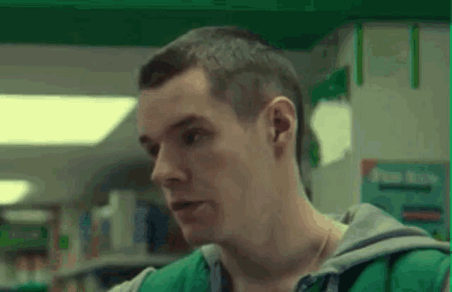 a man in a green vest is standing in a pharmacy .