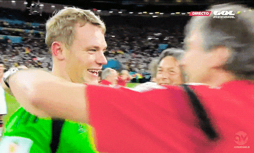 a man in a green shirt is hugging another man in a red shirt with gol written on the screen