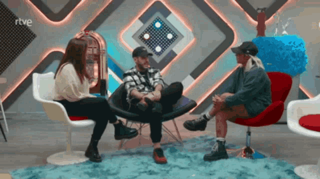 three people sit in chairs in front of a jukebox with rtve written on the bottom