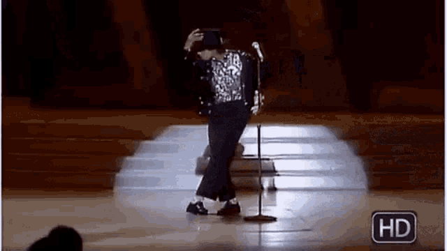 a man is dancing on a stage with a microphone in front of him .