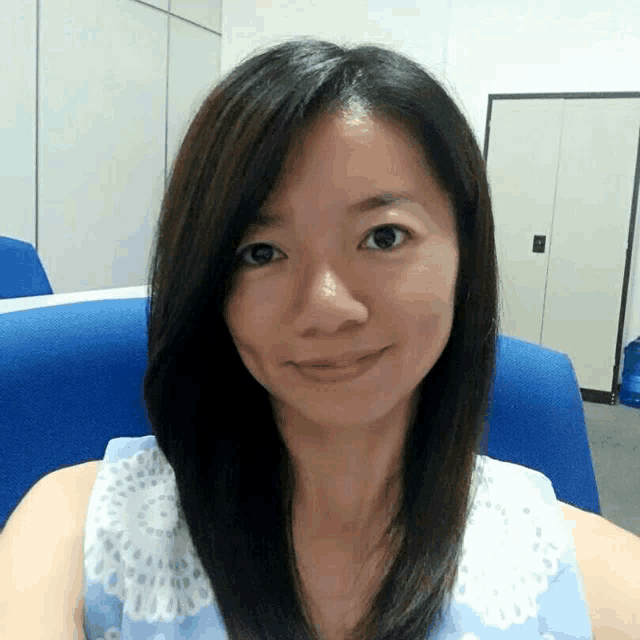 a woman sitting in a blue chair taking a picture