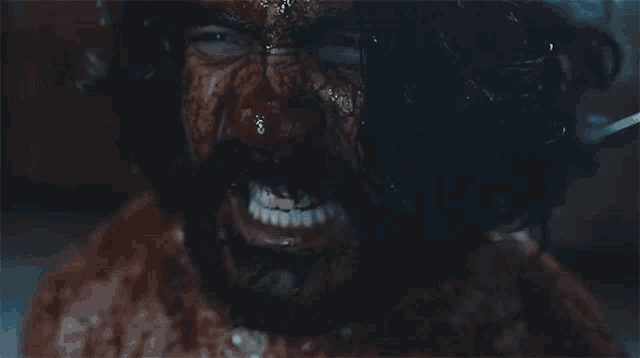 a man with a beard is covered in blood and smiling