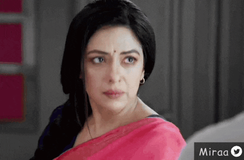 a woman in a pink saree is looking at the camera with a miraa logo in the corner .
