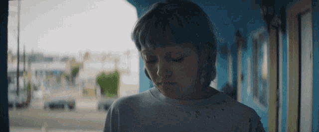 a woman with blue hair is standing in a hallway with a blue wall