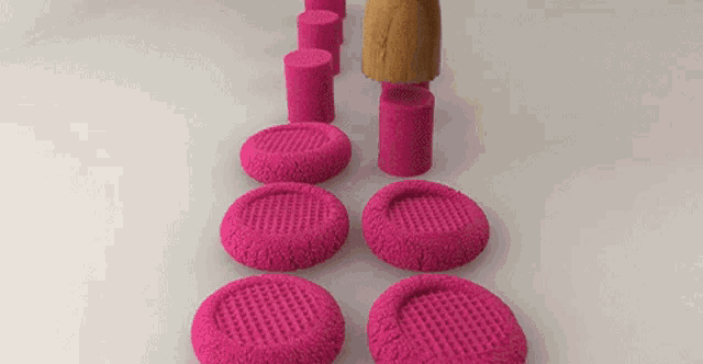 a row of pink circles and cylinders with holes in them