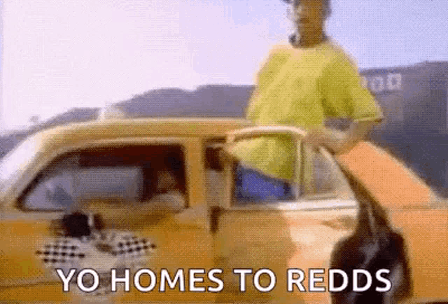 a man is getting out of a yellow car with the words `` yo homes to redds '' written on it .