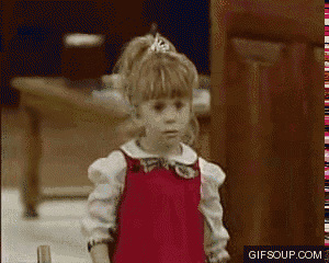 a little girl in a red dress is standing in front of a door with gifsoup.com written in the corner