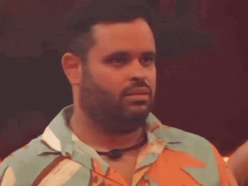 a man with a beard wearing a colorful shirt and a microphone around his neck .