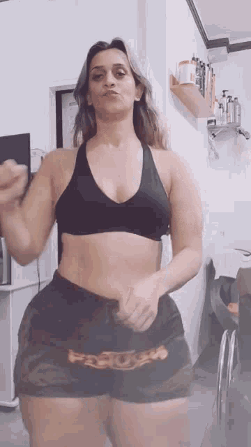a woman in a black top and camo shorts is standing in a room .