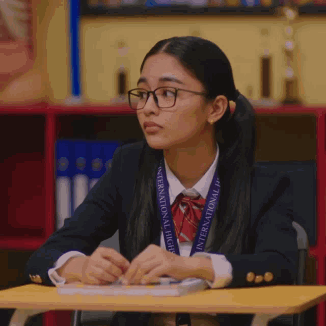 a girl with glasses and a lanyard that says international high