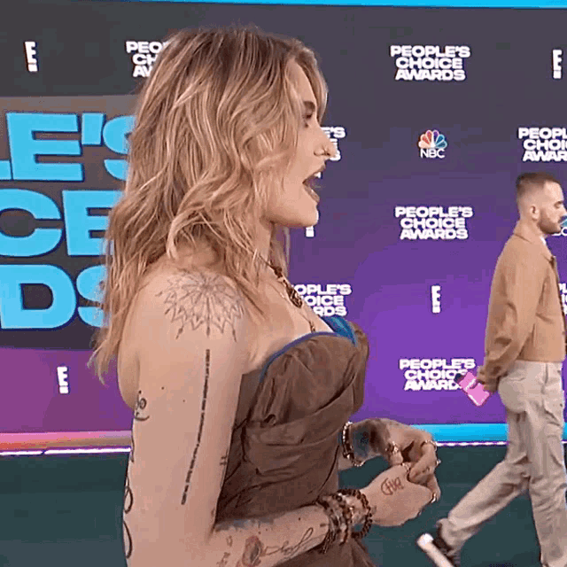 a woman stands in front of a wall that says people 's choice awards on it