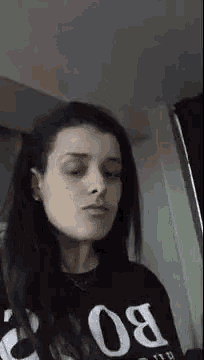 a woman is wearing a black shirt with the word bo on it and making a funny face .