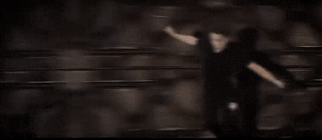 a man in a black shirt is standing in front of a wall