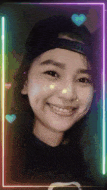 a girl wearing a baseball cap and a black shirt smiles