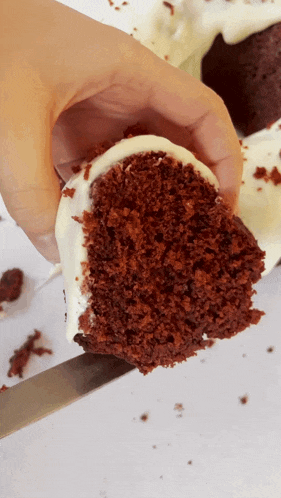 a person is holding a slice of red velvet cake