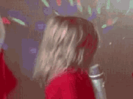 a little girl in a red sweater is holding a microphone in her hand .