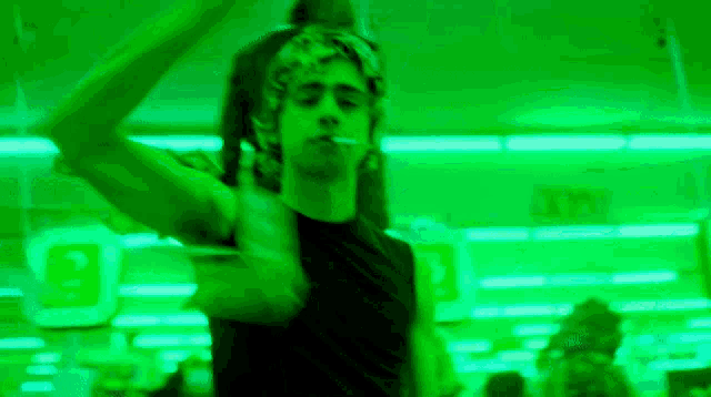 a man is smoking a cigarette in a green room with a sign that says exit
