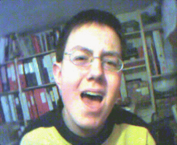 a young man wearing glasses and a yellow shirt is singing