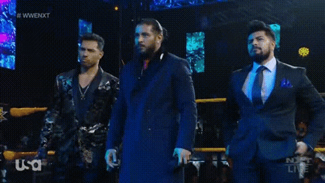 three men in suits are standing in a ring .