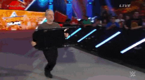 a man is walking down a wrestling ring with a sign that says live on the bottom