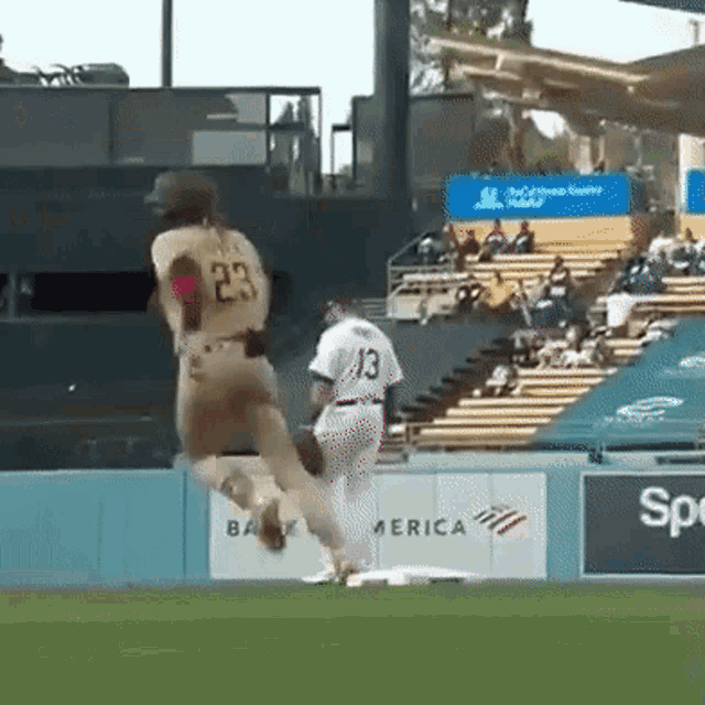 a baseball player with the number 23 on his back is jumping in the air
